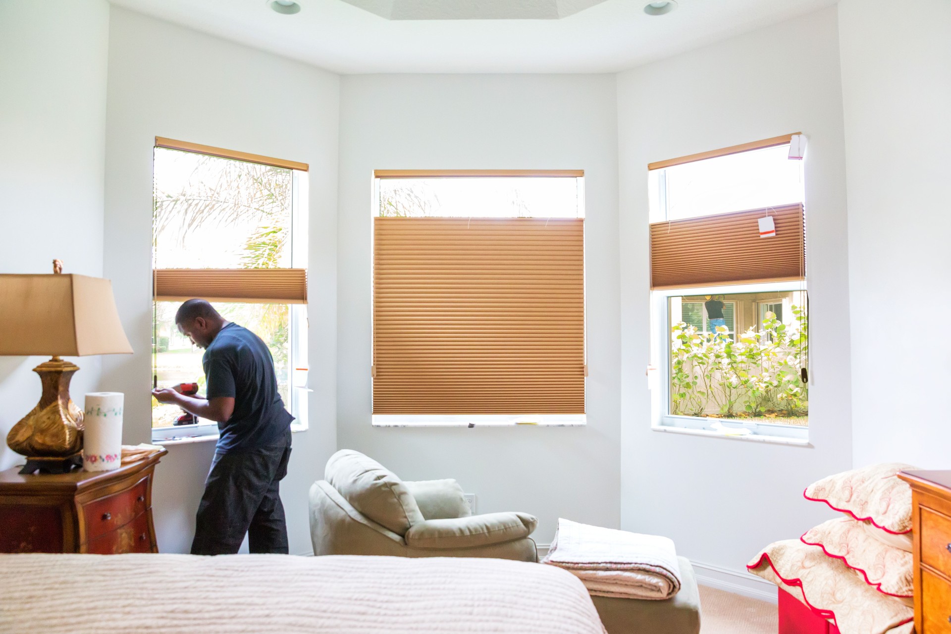 Window treatment installer installs shades in a bedroom